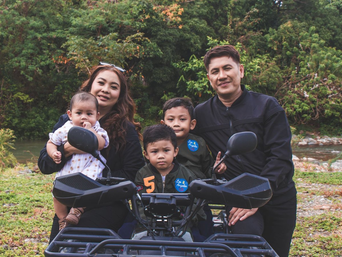 Family with young children posing on a black ATV at the start of a Bali jungle ride