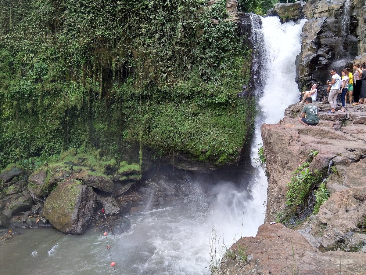 Tourists on the staircase beside Tegenungan waterfall near Ubud Bali with a wide plunge pool below